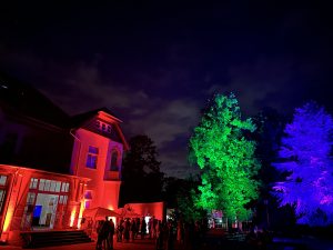 Party vor der gelben Villa mit bunt beleuchteten Bäumen